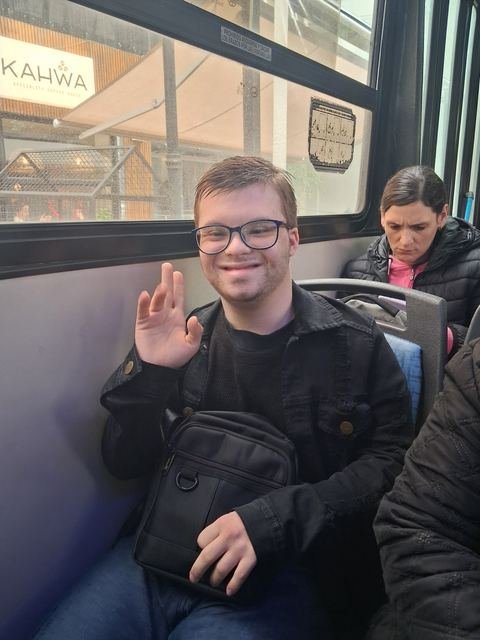 Un participante saludando desde el asiento del colectivo